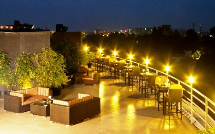 Outdoor rooftop lounge at dusk with lounge seating and string lights in warm golden tones